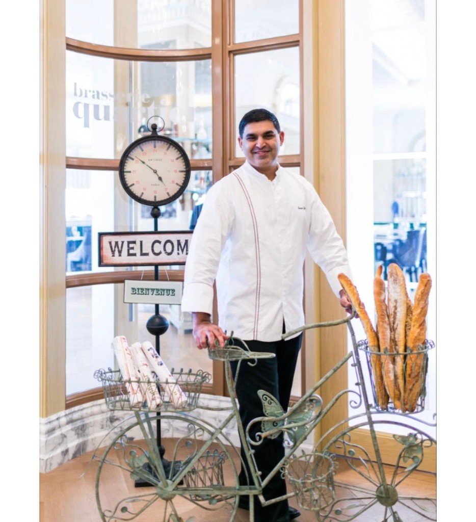Chef Sameer Sehgal at a brasserie entrance, luxury hotel chef in chef whites