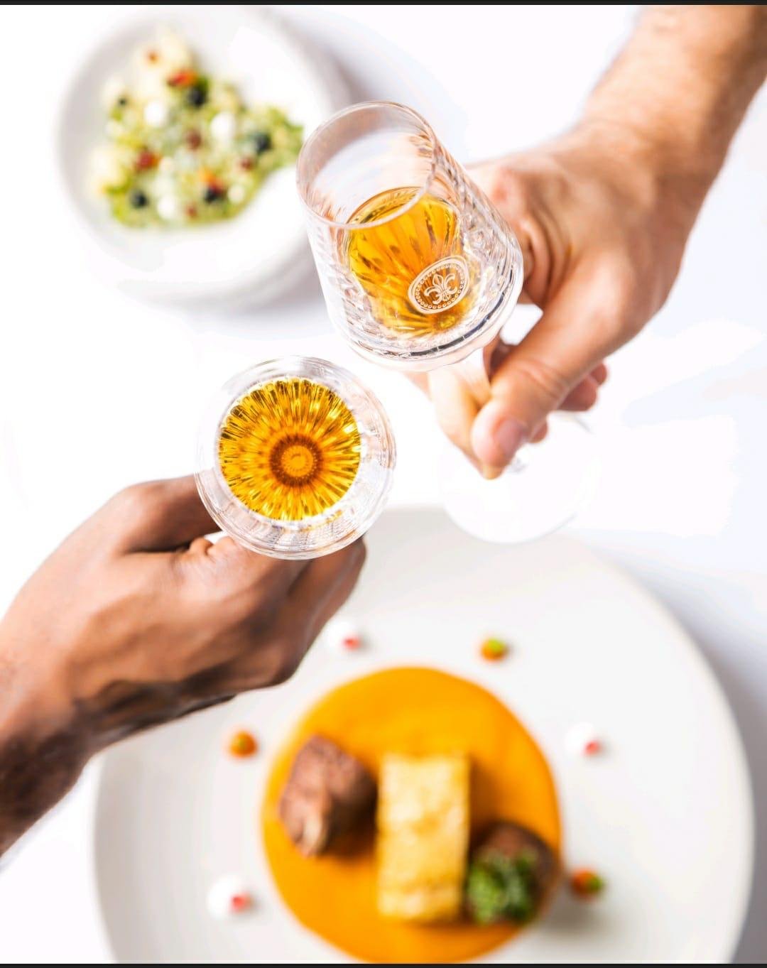 Two glasses of cognac raised over a plated main course