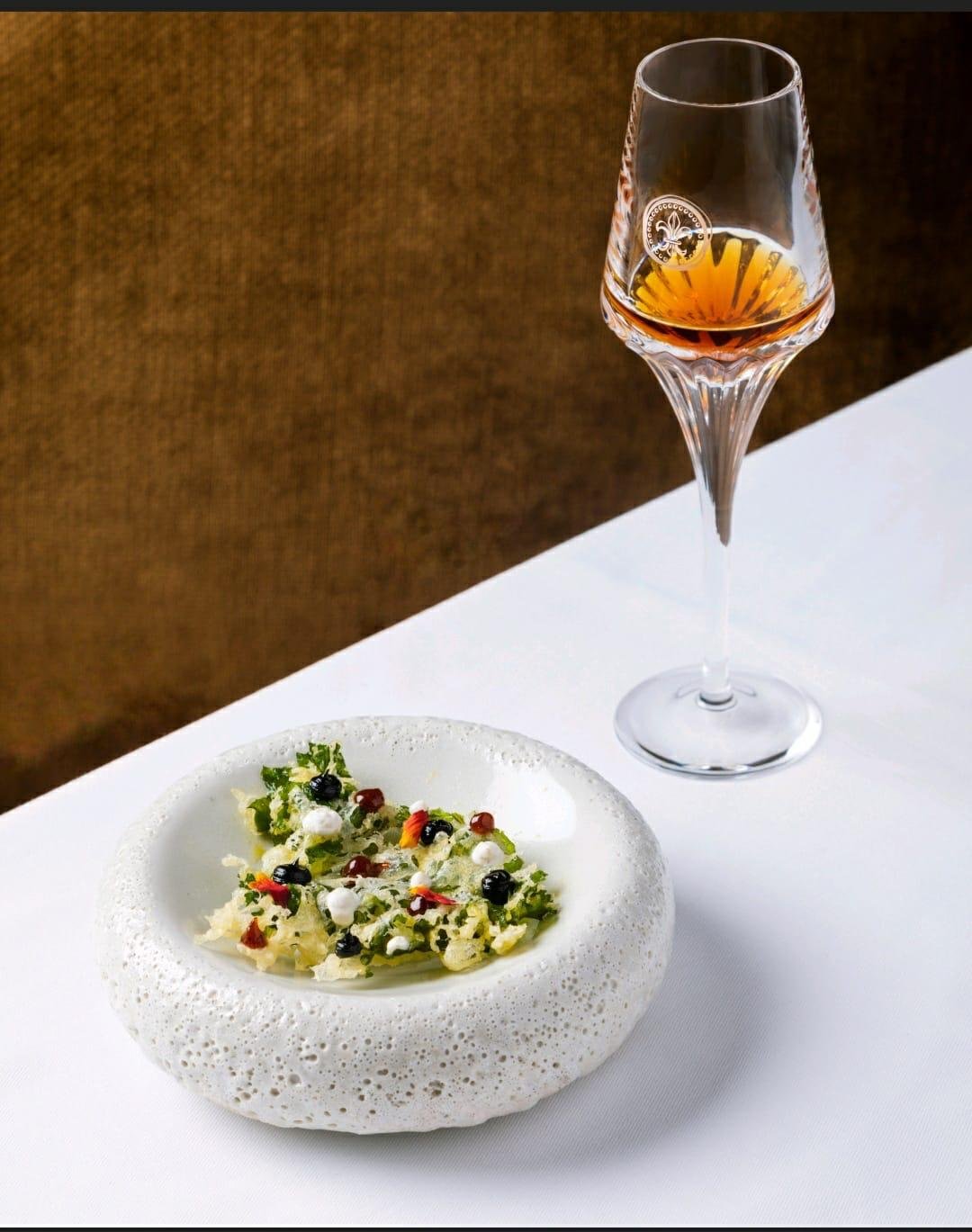 Herb and citrus salad in a textured white bowl with cognac